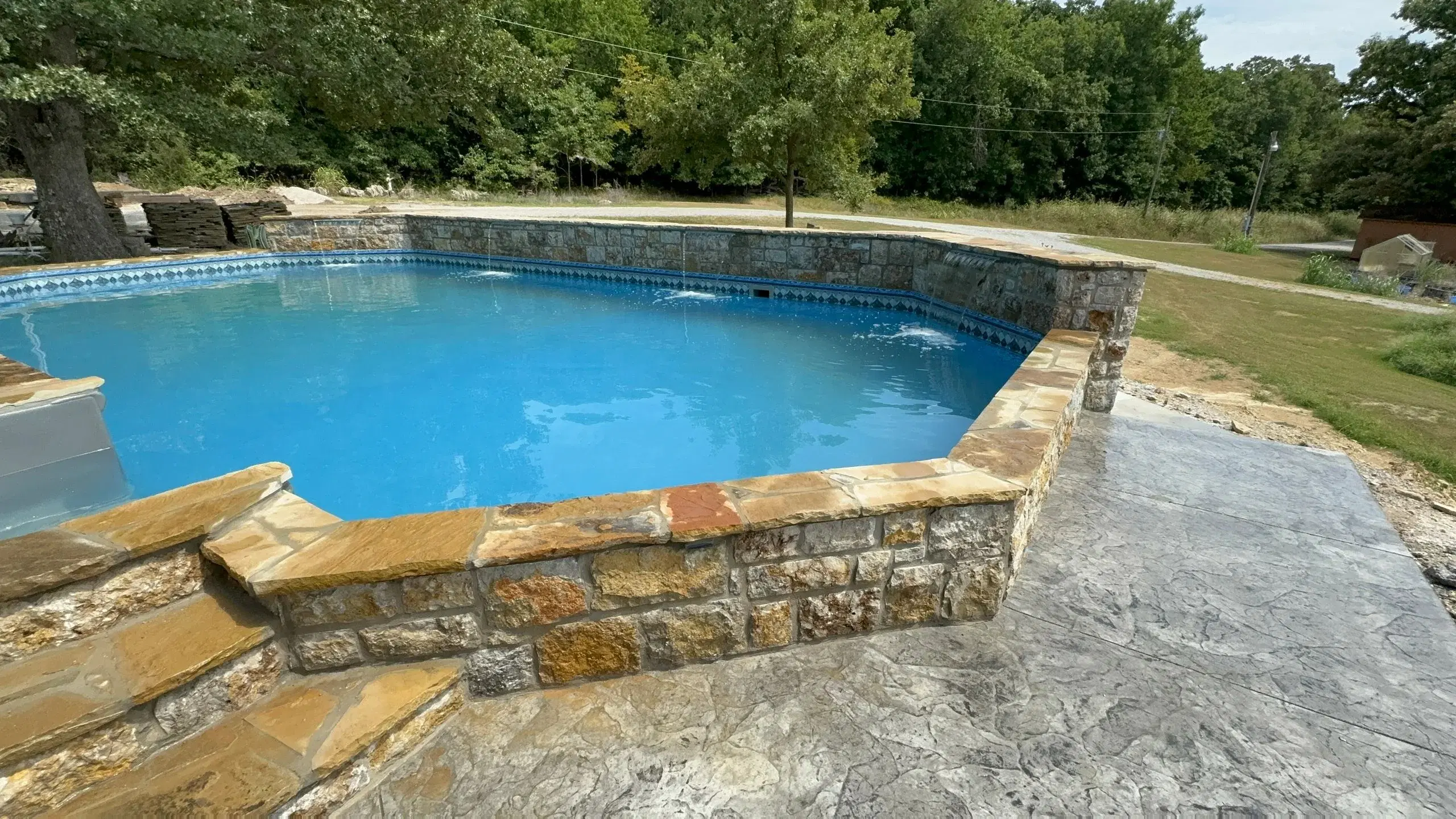 Semi-inground pool on sloped yard in Tulsa, Oklahoma with hillside rock surround